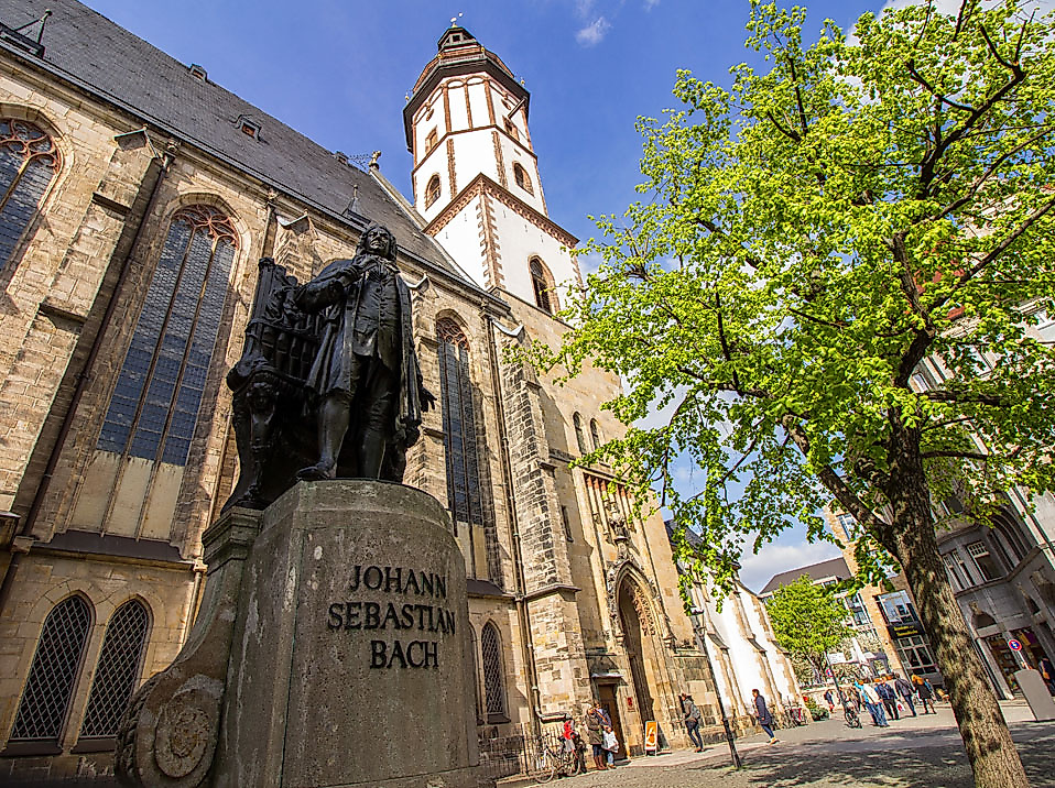 Denkmal von Johann Sebastian Bach vor der Thomaskirche in Leipzig bei Sonnenschein und blauem Himmel.