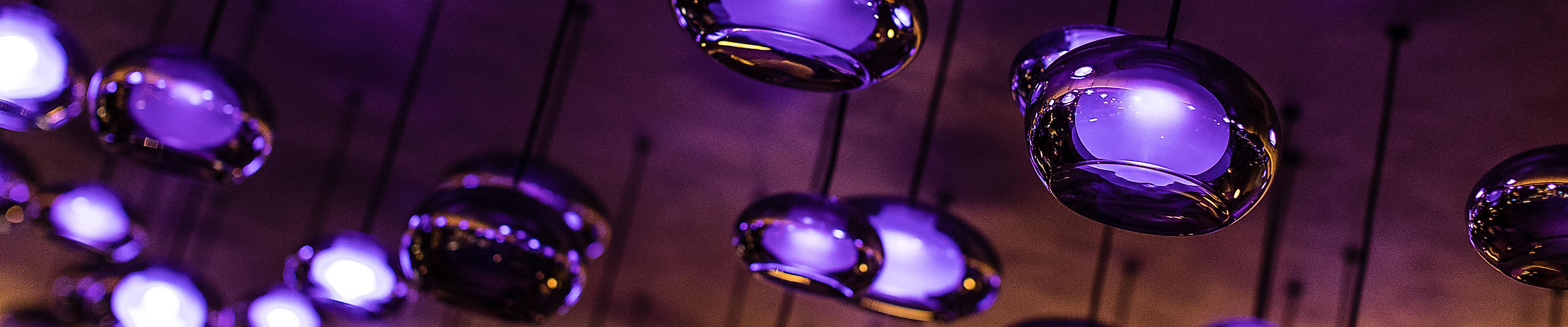 Moderne Deckenbeleuchtung mit violett leuchtenden Spots schafft clubartige Atmosphäre in Pop-Club.