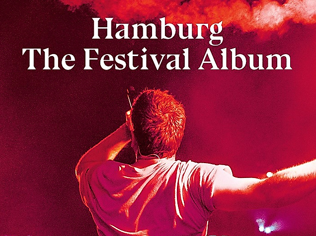 Person mit Bengalo in rotem Licht bei Musikveranstaltung. Text: Hamburg The Festival Collection.