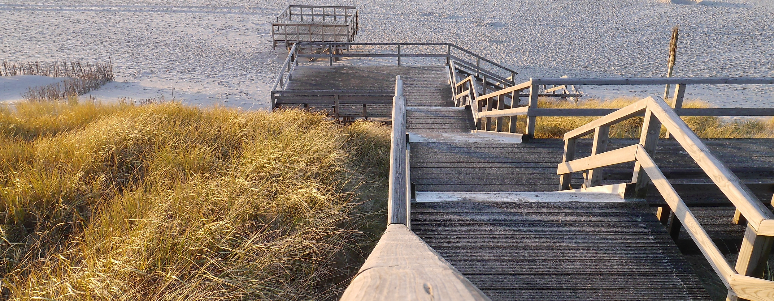 Holztreppe führt durch Dünengras hinab zum Strand und zur Nordsee auf Sylt bei Abendlicht