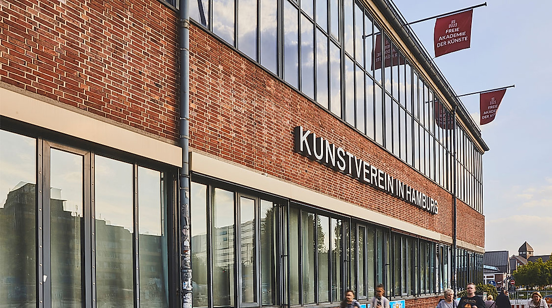 Außenansicht des Kunstvereins in Hamburg mit roter Klinkerfassade, Fahnen und Besuchenden am Eingang