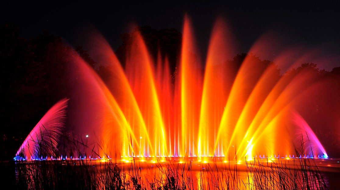 Farbig beleuchtete Wasserfontänen der Wasserlichtspiele in Planten un Blomen bei Nacht