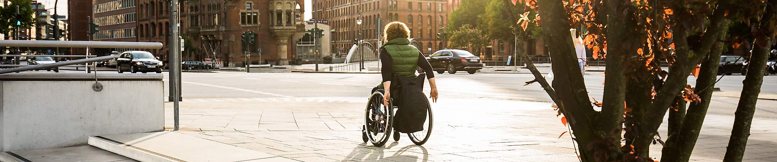 Person im Rollstuhl auf barrierefreiem Weg in der Hamburger Speicherstadt bei Sonnenlicht.