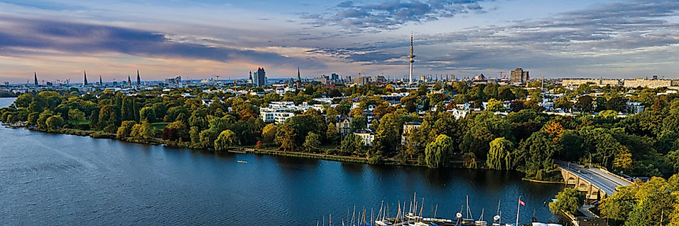 Luftaufnahme der Alster mit Bootsanlegern und grüner Stadtkulisse – Symbol für nachhaltige Veranstaltungen in Hamburg.