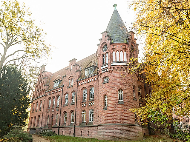 Backsteinfassade des Bergedorfer Schlosses in Hamburg, eingerahmt von herbstlich gefärbten Bäumen