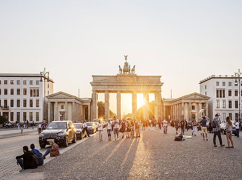 Sonnenuntergang hinter dem Brandenburger Tor in Berlin mit Menschen auf dem Pariser Platz.
