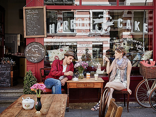 Menschen sitzen vor einem roten Straßencafé im Schanzenviertel und unterhalten sich bei Getränken.