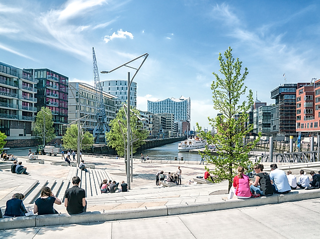Magellanterrassen in der HafenCity Hamburg mit Menschen auf Sitzstufen und Blick auf den Traditionsschiffhafen