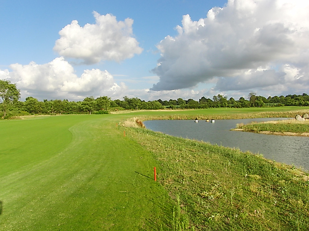 Spielbahn mit Wasserhindernis auf dem Golfplatz Golf am Donner Kleve bei Hamburg unter wolkigem Himmel