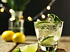 Erfrischender Cocktail mit Limette und Minze auf Holztisch, stimmungsvolle Lichter im Hintergrund