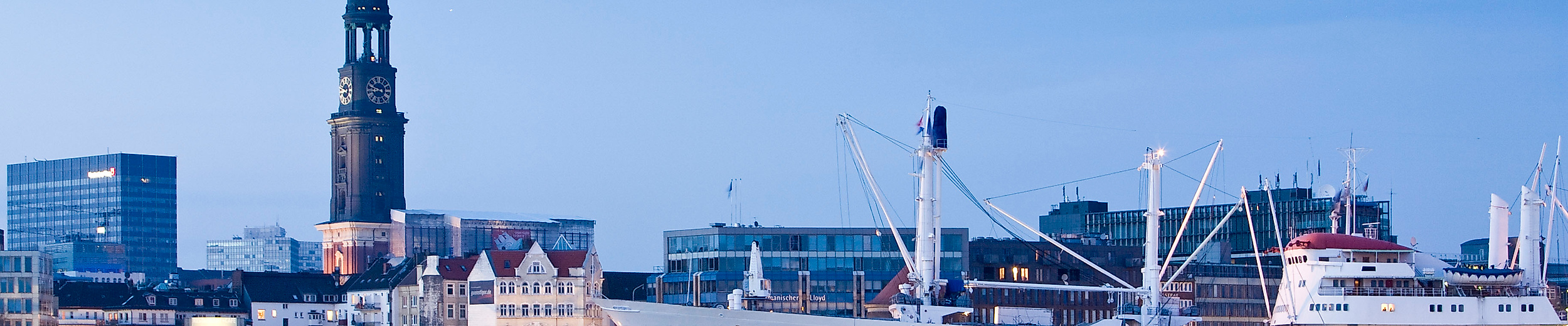 Cap San Diego im Hamburger Hafen bei Abendlicht mit Blick auf den Michel und die Stadt