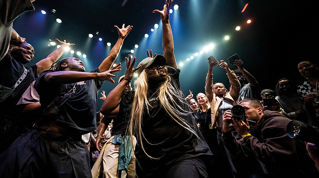 A group of performers raise their arms high.