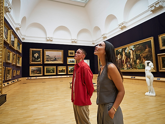 Zwei junge Erwachsene betrachten Bilder in einem historischen Saal der Kunsthalle Hamburg.
