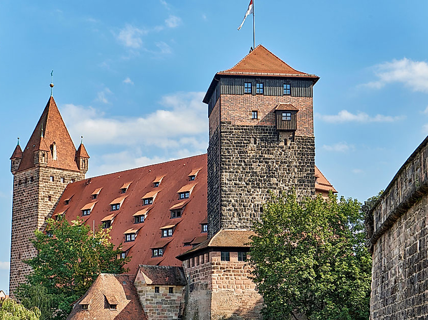 Blick auf die Nürnberger Kaiserburg mit historischen Sandsteinmauern und roten Ziegeldächern an einem sonnigen Tag.