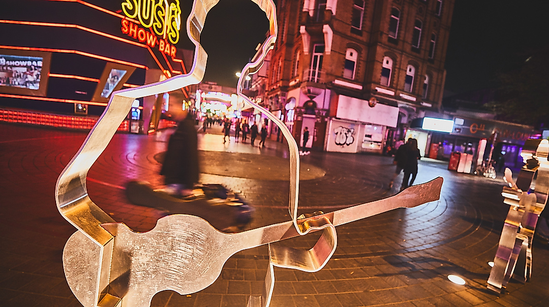 Beleuchtete Skulptur am Beatles-Platz auf der Reeperbahn bei Nacht mit Neonlichtern