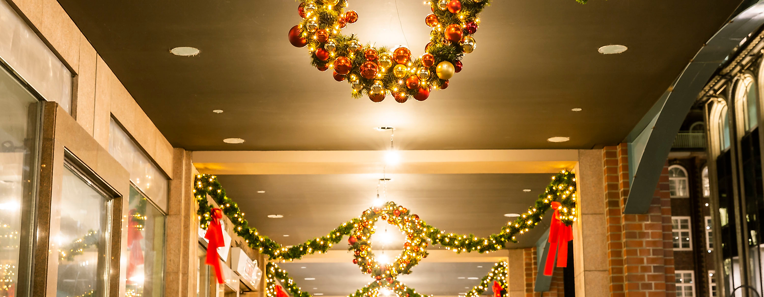 Festlich geschmückte Passage mit Lichterkränzen und Tannengirlanden in weihnachtlicher Abendstimmung