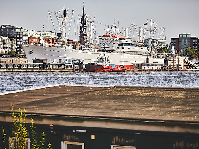 Museumsschiff Cap San Diego im Hamburger Hafen, Blick über die Elbe auf das weißrote Frachtschiff vor maritimer Kulisse