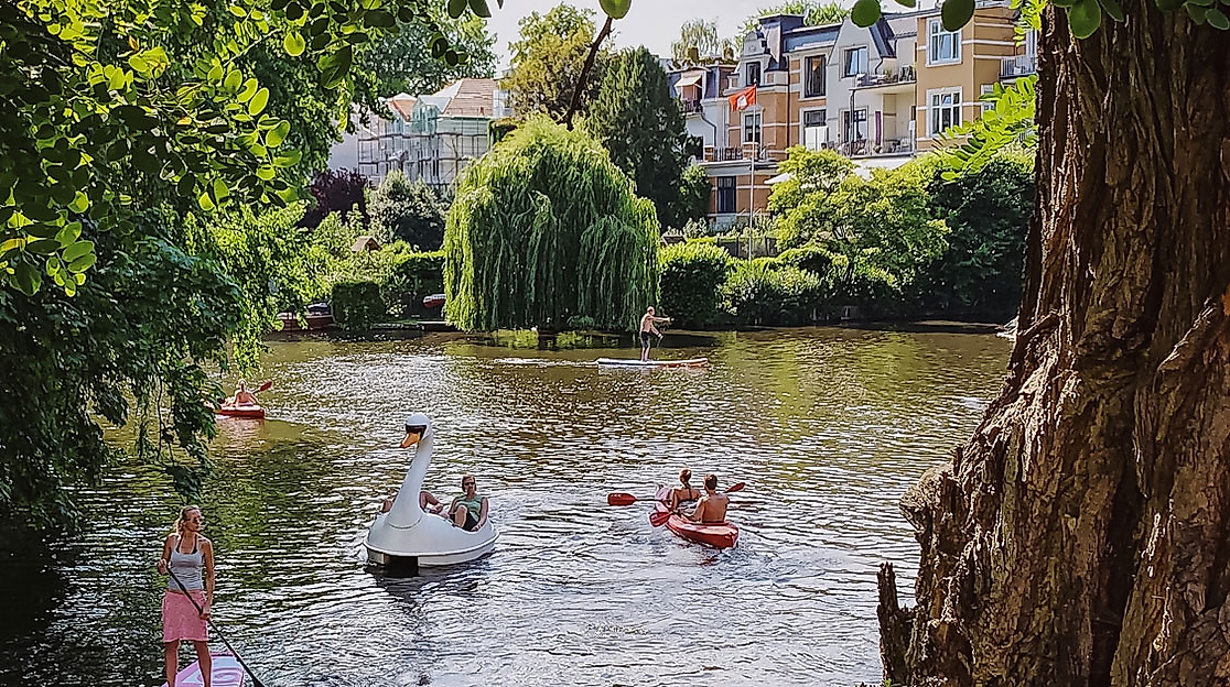Sommerliche Kanuszene auf einem Alsterkanal in Hamburg mit umgebenden Bäumen und Wohnhäusern im Hintergrund