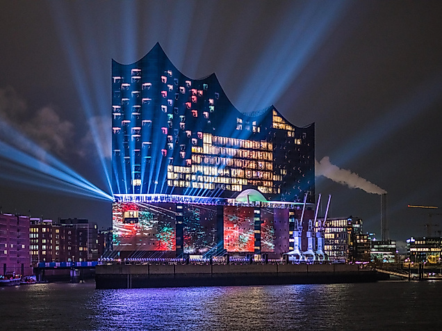 Illuminierte Elbphilharmonie bei Nacht mit bunter Lichtshow und Spiegelungen auf der Elbe