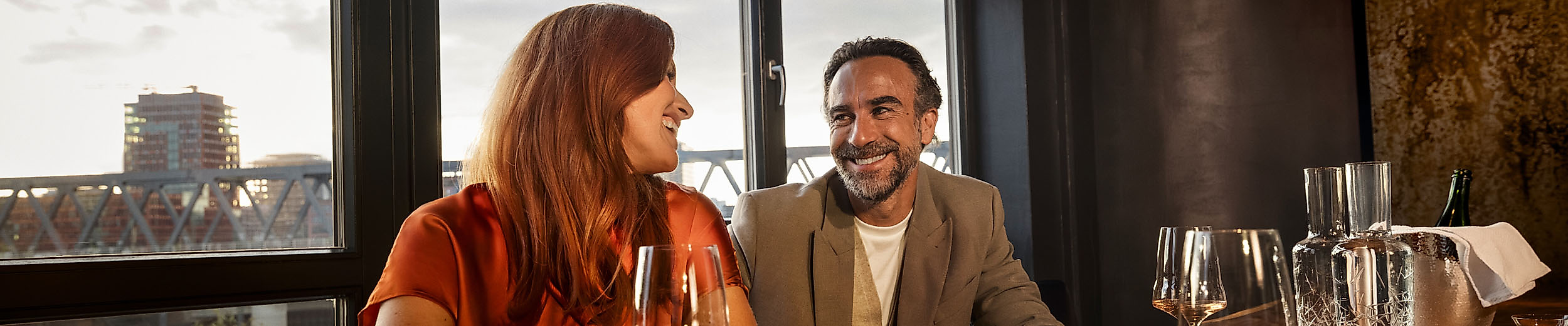 A couple sits at a table in the restaurant with a glass of wine 100/200