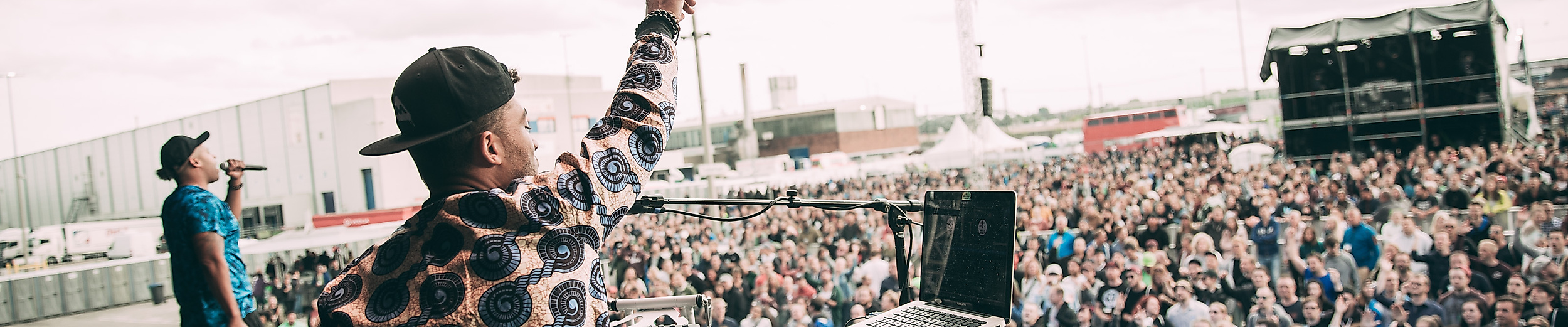 Beginner auf Festivalbühne vor tanzendem Publikum bei Open-Air-Event 