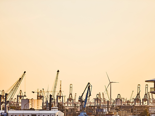 Hafenkräne im Hamburger Hafen bei Sonnenuntergang vor goldenem Himmel