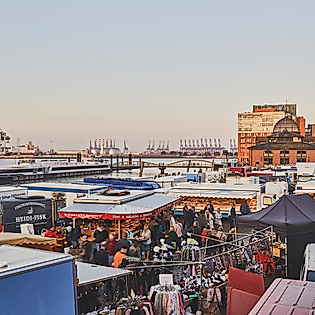 Dicht besuchter Hamburger Fischmarkt mit Marktständen und Blick auf Elbe und Hafen bei Tagesanbruch
