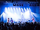 Publikum vor hell beleuchteter Bühne bei Live-Konzert mit Band und Scheinwerfern
